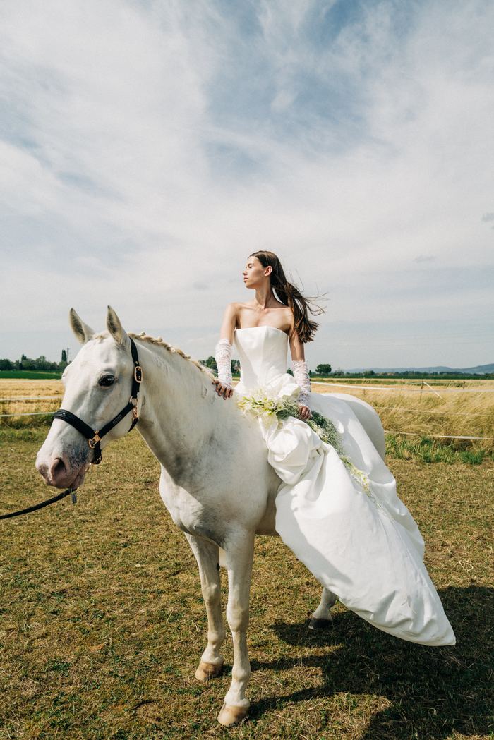 Braut im Kleid auf dem weißen Pferd