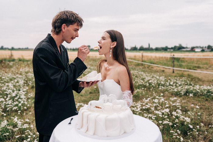 Der Bräutigam füttert die Braut mit einem Stück Hochzeitstorte